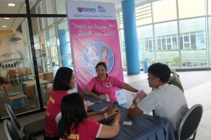Ms. Corpuz (in shirt with DSWD logo), SWAD Staff, answer queries from a prospective adoptive parent (in white shirt) at the Adoption Help Desk in SM City Cauayan, Isabela.